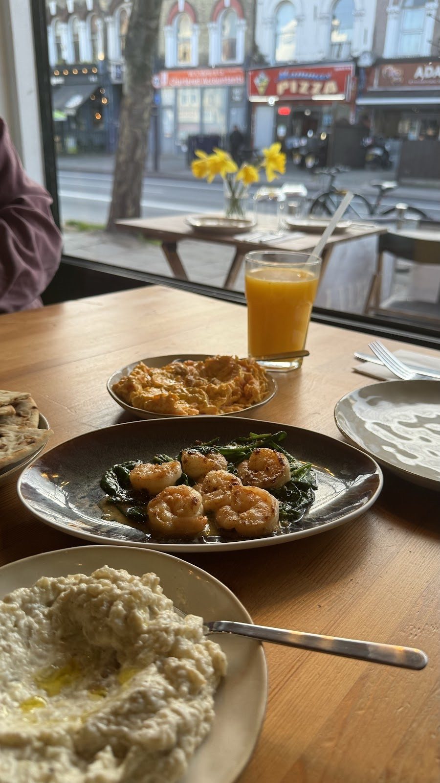 A window table with falafel on greens, hummus, flatbread and orange juice, Brixton Hill outside