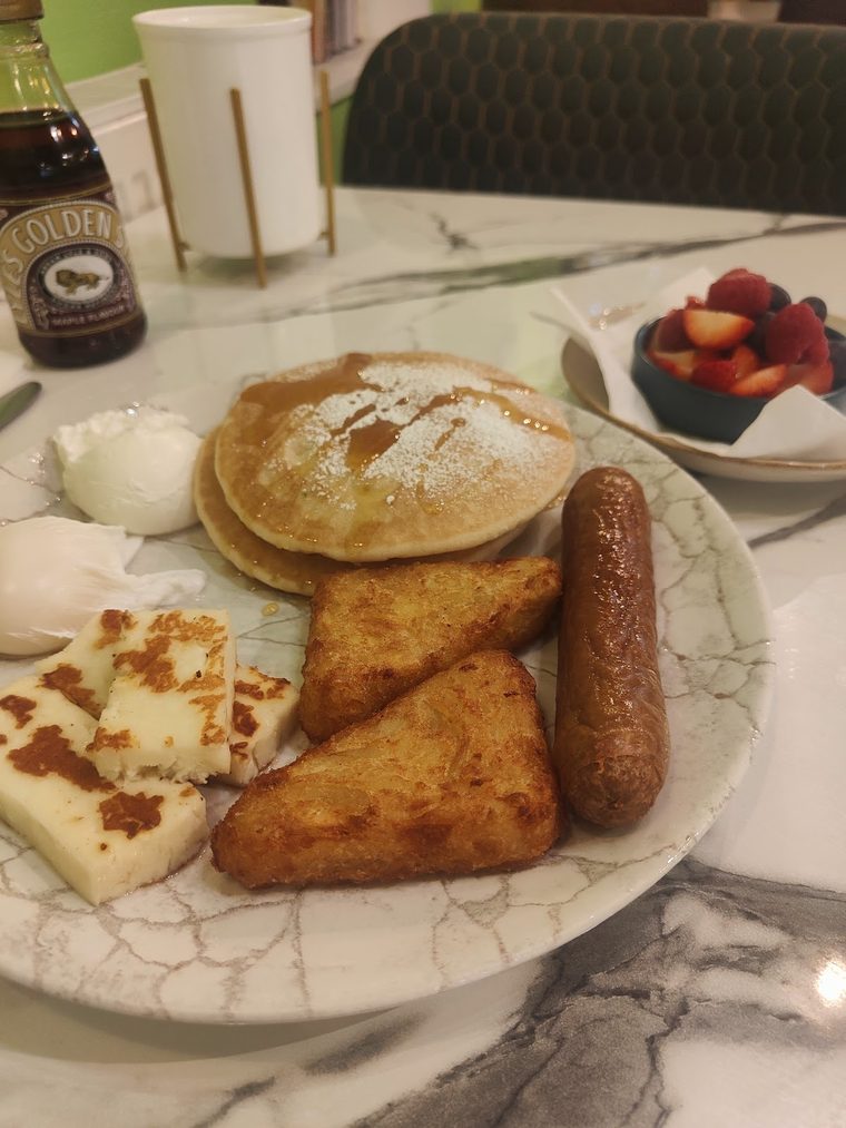 Pancakes, hash browns, halloumi, sausage and poached egg on a marble table