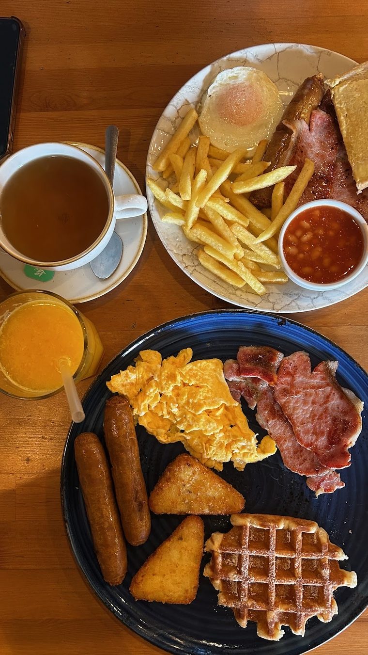 Scrambled egg, bacon, waffle and hash browns with tea and orange juice